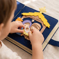 Close-up of a child's hands placing a felt figure on the hand-stitched nativity page