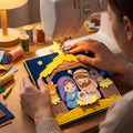 Hands stitching the yellow felt star onto the navy nativity quiet book at a sewing machine