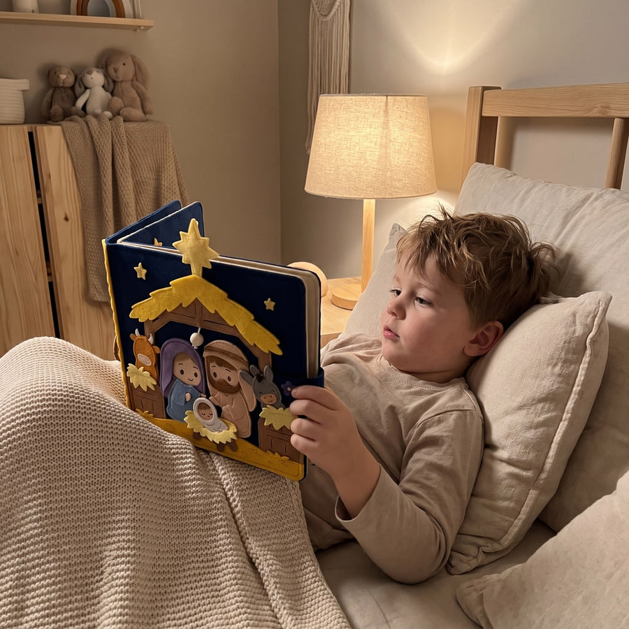 Child in bed at night reading the felt nativity quiet book by lamplight