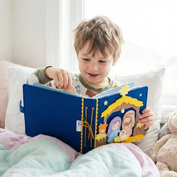 Boy in bed reading the handmade felt nativity quiet book